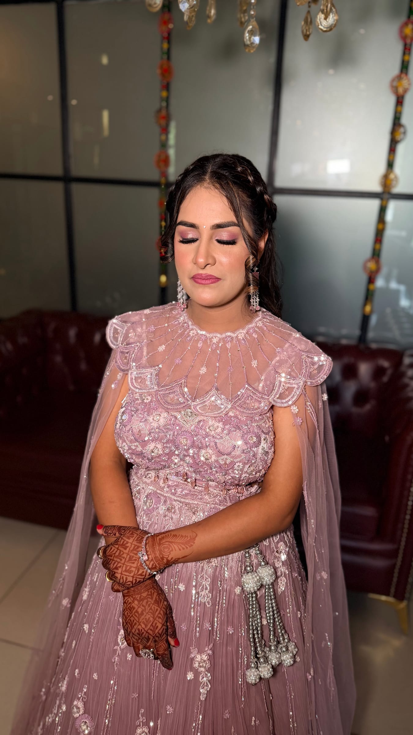 A bride in a mauve cape gown with mehndi on her hands